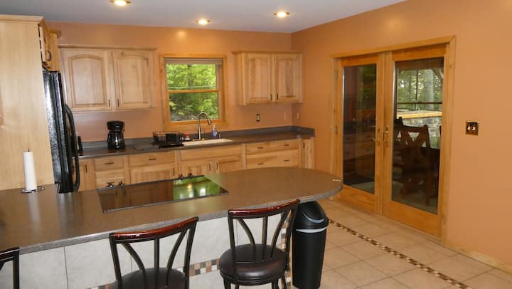 Full kitchen with island, dining table, and wooded view